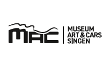 Das Logo des MAC Museum Art & Cars in Singen ist in Schwarz auf weißem Hintergrund dargestellt. Links ist das stilisierte "MAC"-Kürzel mit einer wellenartigen Linie darüber zu sehen. Rechts davon, durch einen vertikalen Strich getrennt, steht in zwei Zeilen "MUSEUM ART & CARS" und darunter "SINGEN".
