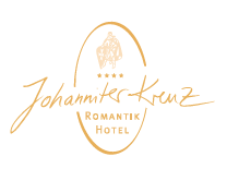 Das Logo des Romantik Hotel Johanniter-Kreuz zeigt eine stilisierte, ovale Form in einem warmen Goldton. Innerhalb des Ovals befindet sich oben eine stilisierte Darstellung eines Ritters mit Schild und Schwert, darüber und darunter sind Teile des Ovals unterbrochen. Unter dem Ritter sind drei goldene Sterne horizontal angeordnet. Darunter steht in geschwungener, handschriftlicher Schrift ebenfalls in Gold "Johanniter-Kreuz". Unterhalb des Namens, innerhalb des unteren Teils des Ovals, steht in kleinerer, serifenloser Goldschrift "ROMANTIK HOTEL". Der Hintergrund ist weiß.