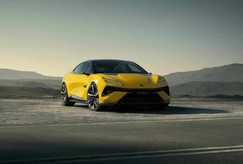 Ein leuchtend gelber Lotus Emeya Sport-Limousine steht auf einer Straße mit schwarzem Dach vor einer weiten Berglandschaft bei klarem Himmel.