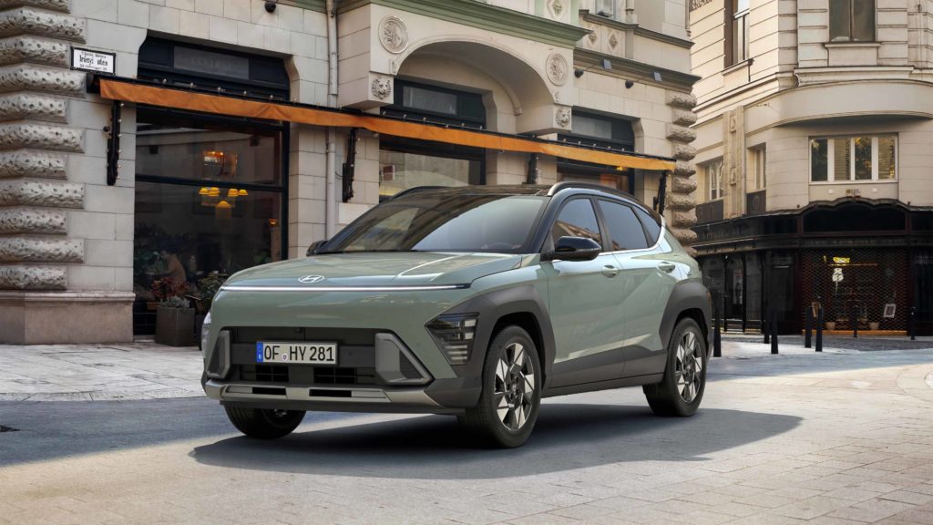 Ein mintgrüner Hyundai Kona SUV steht in einer belebten Straße mit klassischer europäischer Architektur im Hintergrund.