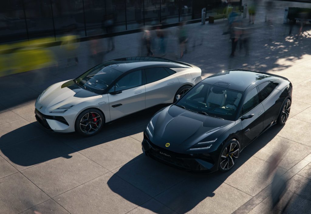 Zwei sportliche Lotus Emeya, ein weißer und ein schwarzer, parken nebeneinander auf einem modernen Platz