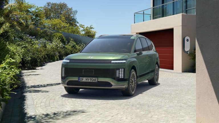 Ein grüner Hyundai IONIQ 9 steht auf einer gepflasterten Einfahrt vor einem modernen Haus mit Ladestation.