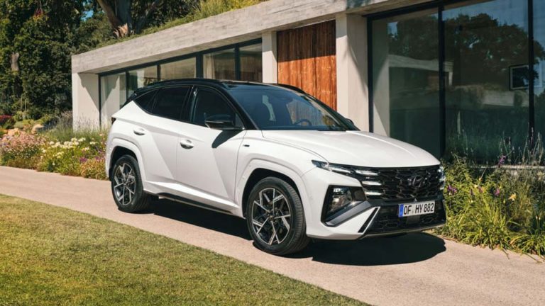Ein weißer Hyundai Tucson steht auf einer gepflegten Einfahrt vor einem modernen Haus.