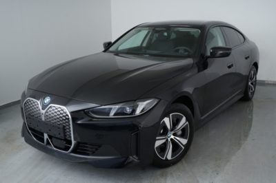 Eine schwarze BMW i4 eDrive35 Gran Coupé steht auf hellem Boden in einem Fotostudio.