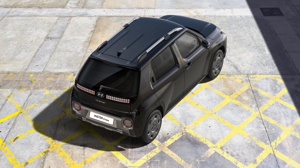 Der dunkle Hyundai INSTER Cross ist von oben hinten auf einem Parkplatz mit gelben Markierungen zu sehen.