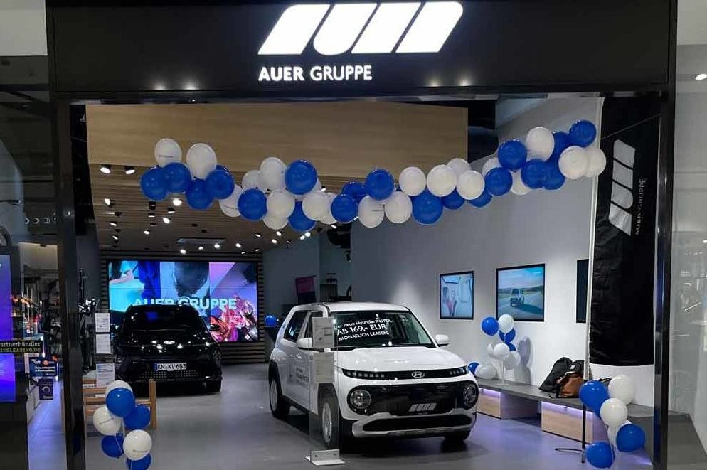Eine AUER GRUPPE Ausstellung mit zwei Hyundai Modellen und blauen und weißen Ballons in einer Shopping Mall.